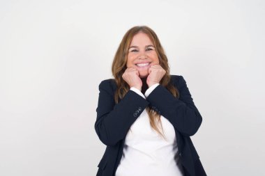 Avrupa 'lı orta yaşlı kadının portresi duygularla dolup taşıyor, heyecan ve mutluluğu kapalı gözlerle ve ellerle ifade ederken gri arka planda geniş bir gülümsemeyle..