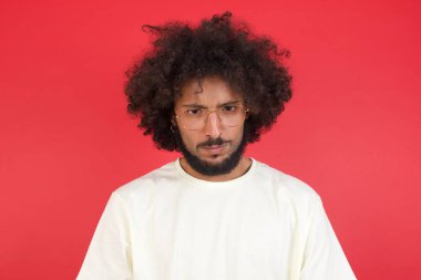 Kızıl duvara karşı poz veren afro saçlı genç adam. 