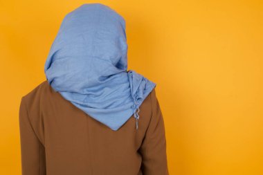 Sarı duvara dayanmış Afro-Amerikalı müslüman bir kadının arka yüzü. Stüdyo Çekimi. 