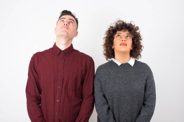  Sıradan kıyafetler giyen çift gizemli bir gülümsemeyle yukarı bakıyor. Güzel gülümseyen kız, gri duvara bakıyor..