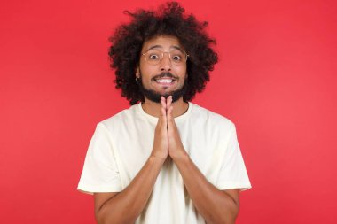Afro saçlı genç adam kırmızı duvara karşı lütfen diyor.   