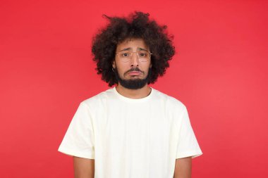 Afro saçlı genç adam kırmızı duvara karşı üzgün. 