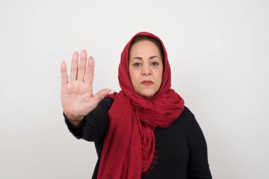 Müslüman, olgun bir kadın avucunun içi gibi jestleri kesiyor. Gri arka planda izole edilmiş yüzünde negatif ve ciddi bir jest olan uyarı ifadesi. Stüdyoda poz veren başörtüsü takan orta yaşlı bir Arap kadın.