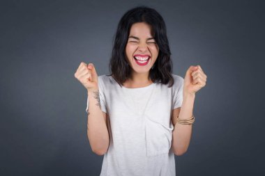 Kafkasyalı esmer kadın başarısını ve zaferini sevinçle kutluyor ve yumruklarını zevkle sıkıyor. Hedeflerine ve hedeflerine ulaşmaktan mutlu olan şanslı kadın. Olumlu duygular, duygular.