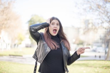 Genç ve kafası karışmış bir kadın parkı işaret ediyor.