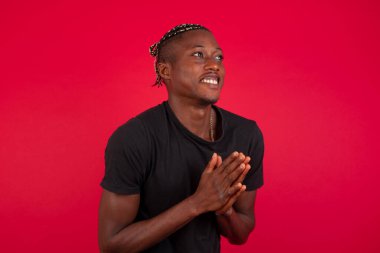 Genç ve başarılı Afrikalı Amerikalı adam sarı duvara yaslanmış, mutlu, gülümseyen ve alkışlayan bir alkış ile tebrik ediyor..