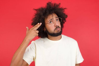 Kızıl duvara karşı silahlı afro saçlı genç adam. 