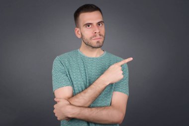 Moda reklamcılığı ve tanıtım metinleriniz için gri arka planınızın fotokopisini çekerken heyecanlı bir moda çocuğu mutlu bir şekilde işaret ediyor..