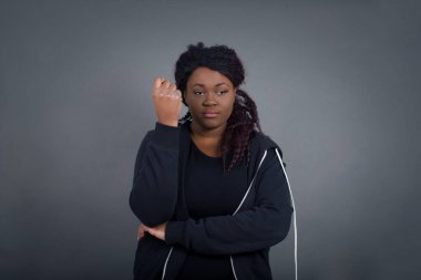 Yüzüne yakın eli olan ve şüpheli ve şüpheci bir ifadeyle kameraya bakan şık bir Afro-Amerikan kadının izole edilmiş portresi. Gri arkaplan üzerinde izole.