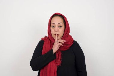 Sırrımı söyleme ya da yüksek sesle konuşma, lütfen! Duygusal olarak şaşırmış olgun Müslüman bir kadın sessiz ol der, sessiz ol der, sırlarını açığa vurmaktan korkar, gri stüdyo duvarına karşı durur..