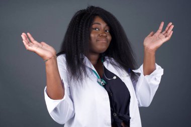 Belki evet ya da hayır. Şüpheli Afrikalı Amerikalı kadın doktor şaşkınlık içinde omuz silkiyor, karar vermeye çalışıyor. Beyaz beton duvarın üzerinden neyi izole etmek istediğini şaşırtıyor. Tereddüt ve belirsizlik.