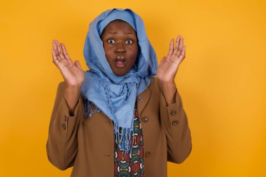 Sürpriz konsept. Şaşırmış, afro-amerikan Müslüman bir kadının portresi. İnanması güç, ağzı açık, yüzüne yakın elleri olan bir kadın. Olumlu duygu yüz ifadesi vücut dili. 