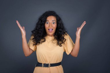 Neşeli esmer kadın ellerini kaldırıyor, mutluluk dolu gözleriyle büyük başarılarını kutluyor..