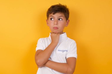 Sarı duvara karşı düşünen tatlı çocuk.  
