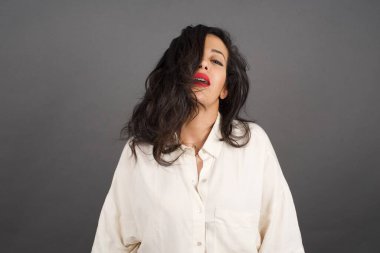 Gri arka planda gelişigüzel giyinmiş güzel esmer kadın..  