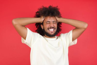 Kızıl duvara gülüp duran afro saçlı genç adam.   
