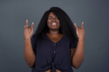 Bu dünyayı sallamak için doğmuşum. Neşeli Afrikalı Amerikalı kadın yüksek sesle bağırıyor ve kollarını kaldırarak ya da rock hareketleriyle gösteriyor. Konserde olmanın heyecanını dile getiriyor..