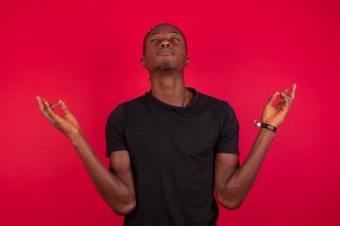 Meditasyon, din ve ruhani uygulamalar. Yakışıklı Afro-Amerikalı adam sabah uyandıktan sonra evde yoga yapıyor, gözlerini kapalı tutuyor, Mudra jestinde parmaklarını tutuyor..