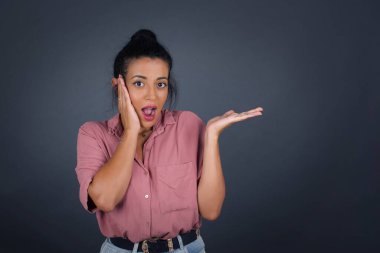 Neşeli genç bayan bir şeyler gösteriyor. Bir eli kafasında, diğer eliyle işaret ediyor..