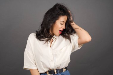 Gayri resmi giyinmiş güzel esmer kadın. Gri arkaplanda duruyor. 