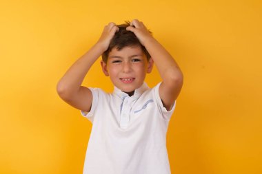 Sarı duvara yaslanmış elleri başında sevimli bir çocuk.  