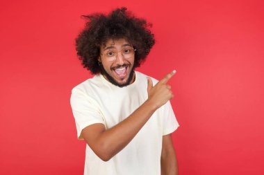 Kızıl duvarı işaret eden afro saçlı genç adam.   