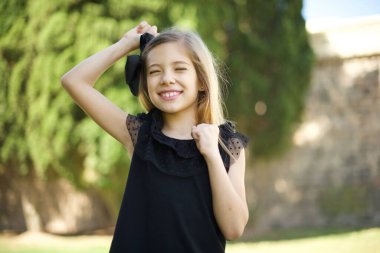 Siyah elbiseli çekici beyaz kız zaferi kutluyor yumruklarıyla havayı yumrukluyor ve parlak dişli bir gülümsemeyle. 