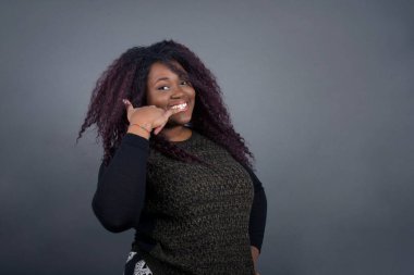 Çekici Afro-Amerikan kadın günlük kıyafetlerle telefon konuşmasını taklit ediyor, cep telefonu tutuyormuş gibi kulağına yakın duruyor, kendine güveni tam bir yüz ifadesi var. Ara beni.!