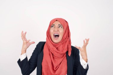 Çığlık, nefret, öfke. Duygusal kızgın, güzel Müslüman kadın siyah ceket giyiyor ve mavi stüdyo arka planında tesettür çığlıkları atıyor. Duygusal, genç yüz. Yarım boy kadın portresi. İnsani duygular, yüz ifadesi kavramı. Moda renkleri