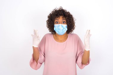 Yüz maskesi takan ve günlük kıyafet giyen kadın beyaz stüdyo arka planında izole edilmiş.
