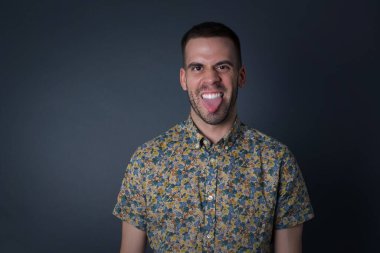 Vücut dili. Gri duvara karşı poz veren, suratını asan, bir şeyden tiksindiğini gösteren, stresli, hoş bir adam..