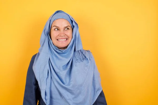 具有特殊外表的中年穆斯林女性形象会咬紧牙关 困惑地将目光投向一边 意识到自己的错误 并在你的广告或促销背景下与复制区域对着干 — 图库照片