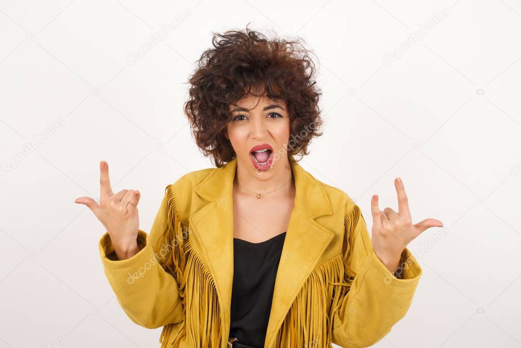 Beautiful  woman in suede jacket showing hrns gesture  studio shot