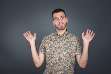 Kafası karışmış, kolları açık, omuzlarını silkip 