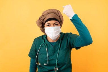 Kendine güveni tam bir Arap kadın doktor. Yüzünün önünde yumruğunu tutuyor. Sanki dövüşmeye, meydan okumaya, çığlık atmaya ve suratında agresif bir ifade var..