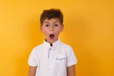 Sarı duvara karşı ağzı açık tatlı bir çocuk.  