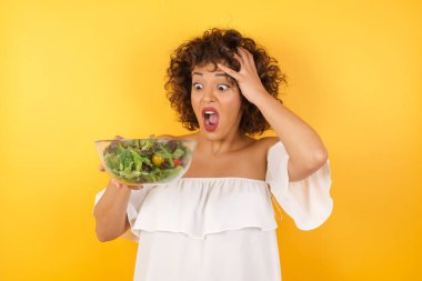 Korkunç, stres, şok. Kafasında salata olan çılgın, güzel bir Arap kadının portresi. İnsani duygular, yüz ifadesi kavramı. Moda renkleri. Ön görünüm