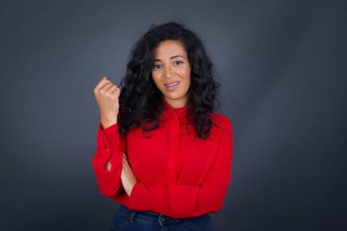 Kıvırcık saçlı, kırmızı tişörtlü neşeli, güzel, esmer bir kadın resmi. Yüzüne yakın eli gri bir duvara dayanıyor. İyi haberleri dinledikten sonra mutlu bir ifadeyle kameraya bakıyorum..