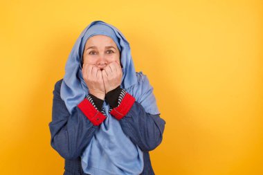 Endişe. Orta yaşlı, tesettürlü, elleri ile ağzını kapatıp dışarıda duran müslüman bir kadının kavramsal görüntüsü. Bir şeyden ya da birinden tırnak yemekten korktun mu?.