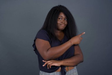 Kamerada poz veren güzel Afro-Amerikalı kadın. İnce bakışlı ve el kol hareketi yapan. Bayan tasarımcı, işaret parmağıyla harika bir ürün sunuyor. Hareket kavramı.