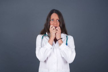 Endişe - güzel bir beyaz kadın doktorun kavramsal görüntüsüdür. Ağzını elleriyle kapatır ve dışarıda durur. Bir şeyden ya da birinin çivi yemesinden korktun mu?.