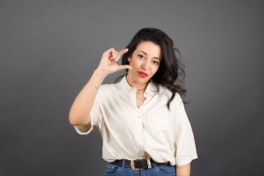 Güzel esmer kadın, gri arka planda gelişigüzel giyinmiş..  