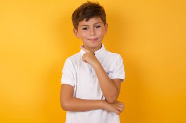Sarı duvara işaret eden sevimli çocuk.  