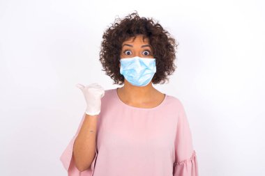 Yüz maskesi takan kadın ve günlük giysiler beyaz stüdyo arka planında izole edilmiş.