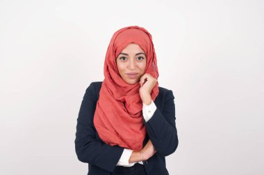 Neşeli Müslüman bir kadının resmi siyah ceket giyer ve tesettür gri duvara karşı durur ve yüzüne yakın durur. İyi haberleri dinledikten sonra kameraya mutlu bir ifadeyle bakmak. Kendine güvenen kız..