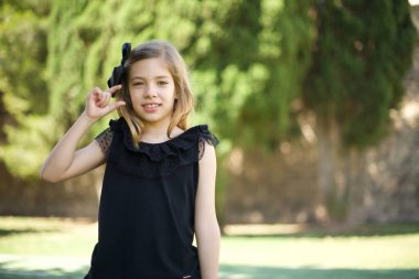 Sarışın, siyah elbiseli, elinde küçük beden, ölçü sembolü olan tatlı bir kız. Kameraya bakıp gülümsüyor. Ölçüm konsepti.