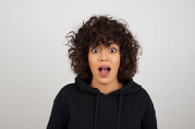 İnsanlar ve ani tepki kavramı. Kapüşonlu şaşırmış bir kadın omuzlarını silker ve bir şey için heyecanlanır.