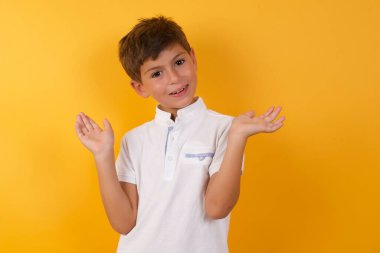 Sarı duvarda açık avuçları olan sevimli bir çocuk.  