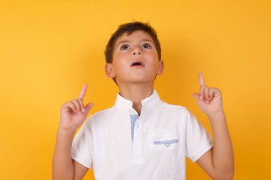 Sarı duvara işaret eden sevimli çocuk.  