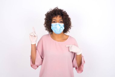 Yüz maskesi takan kadın ve günlük giysiler beyaz stüdyo arka planında izole edilmiş.